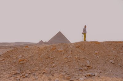A man stands in front of the pyramids