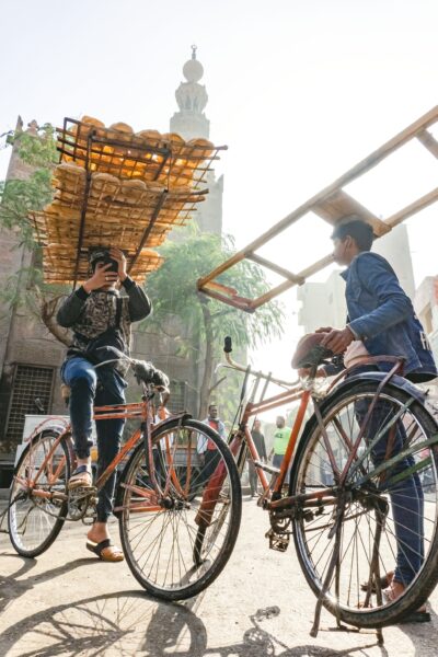 A worker carries bread and rides his bike