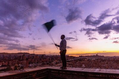 A young man holds a flag to call the pigeons